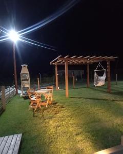a picnic table and chairs under a pavilion at night at Recanto Arvoredo in Entre Rios