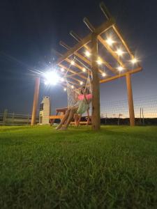 a woman sitting on a swing in a park at night at Recanto Arvoredo in Entre Rios