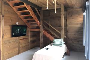 a room with a bed and a tv and wooden walls at Recanto Arvoredo in Entre Rios
