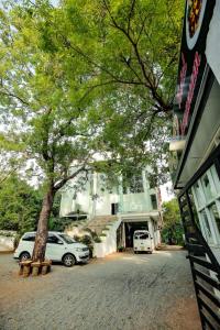 two cars parked in front of a building with a tree at Laaya Neem Dambulla in Dambulla