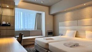 那覇市にあるホテルアクアチッタナハのベッド2台と窓が備わるホテルルームです。