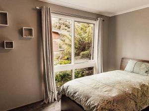 een slaapkamer met een bed en een groot raam bij Luxury Mountain Valley Villa in Mt Evelyn in Mount Evelyn