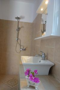 a bathroom with a sink and purple flowers in a vase at Villa Dendron in Aghia Marina