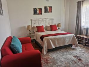 a bedroom with a bed and a red couch at Garden View Home in Brakpan
