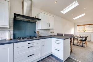 a kitchen with white cabinets and a blue counter top at Peak District views and walks, 3 bed semi in Disley