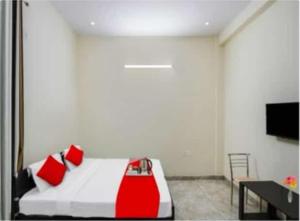 a bedroom with a bed with red pillows and a tv at PLAY - Couple friendly Hotel in Greater Noida