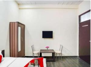 PLAY - Couple friendly Hotel في نويدا الكبرى: غرفة نوم مع مكتب وتلفزيون على الحائط