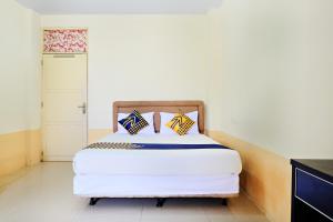 a bedroom with a white bed with two pillows at SPOT ON 2610 Zn Guest House in Makassar