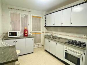 cocina con armarios blancos, fregadero y microondas en Apartamento Céntrico Churriana en Churriana de la Vega
