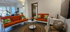 a living room with two orange couches and a table at Ground Floor Apartment near Pereybere Beach in Pereybere