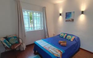 a bedroom with a blue bed with a chair and a window at Ground Floor Apartment near Pereybere Beach in Pereybere