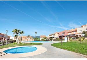 a swimming pool in a resort with palm trees and houses at Paraíso zahara in Zahara de los Atunes