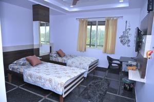 a room with two beds and a desk in it at Anyhour Stay in Gannavaram