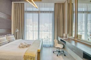 - une chambre avec un grand lit, un bureau et une grande fenêtre dans l'établissement Fully Equipped Cozy Studio in the heart of JVC, à Dubaï