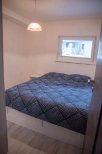 a bedroom with a bed with a blue comforter and a window at Apartma Katja in Škofja Loka