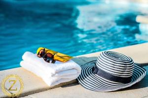 un sombrero y gafas de sol sentados junto a una piscina en Boutique Villa with Rooftop Pool en Netanya