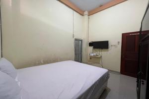 1 Schlafzimmer mit einem weißen Bett und einem TV in der Unterkunft OYO 93683 Kost Naura in Sungguminasa