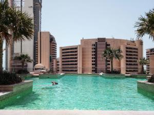 a person swimming in a large pool in a city at Frank Porter - Trident Grand in Dubai