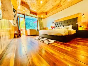 a bedroom with a large bed and a large window at Hotel Himalayan Classic, Manali in Manāli