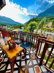 a table and chairs on a balcony with a view at Hotel Himalayan Classic, Manali in Manāli