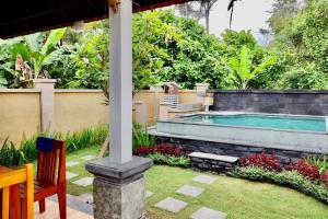 een zwembad in een tuin met een tafel en stoelen bij Serene Picturesque Villa Near Monkey Forest in Mambat