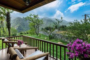 a balcony with two chairs and a view of mountains at Sin Chai Ecolodge in Sa Pa