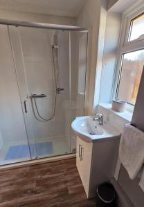 a white bathroom with a shower and a sink at No.6 in Tywyn