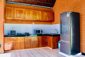 La cuisine est équipée d'armoires en bois et d'un réfrigérateur en acier inoxydable. dans l'établissement Serene Picturesque Villa Near Monkey Forest, à Mambat