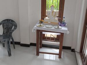 une petite table avec une statue et une chaise dans l'établissement Astral Residence, à Anurâdhapura