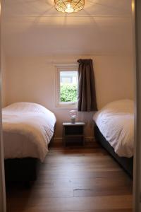 a bedroom with two beds and a window at Hoeve de Zeeanjelier in Sint Annaland