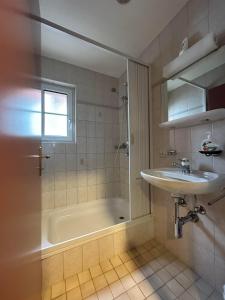 La salle de bains est pourvue d'une douche, d'un lavabo et d'une baignoire. dans l'établissement Touristenheim Bergfreude, à Loèche-les-Bains