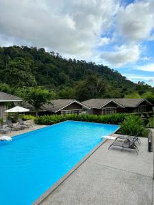 Rebungan Resort Langkawi في كواه: مسبح ازرق كبير مع كراسي وبيوت