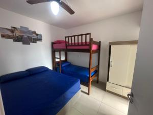 ein Schlafzimmer mit einem Etagenbett und einem blauen Bett in der Unterkunft Lindo Ap - CENTRO- piscina, churrasqueira gourmet, maquina lava e seca e wifi -edifício Jathy in Ubatuba