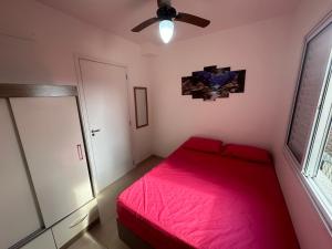 Schlafzimmer mit einem roten Bett und einem Deckenventilator in der Unterkunft Lindo Ap - CENTRO- piscina, churrasqueira gourmet, maquina lava e seca e wifi -edifício Jathy in Ubatuba