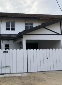 a white fence in front of a white house at Shahanis Homestay. A hotel-like stay experience! in Kijal