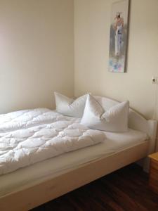 ein Bett mit weißer Bettwäsche und Kissen darauf in der Unterkunft Ferienwohnung Bernhard in Zinnowitz