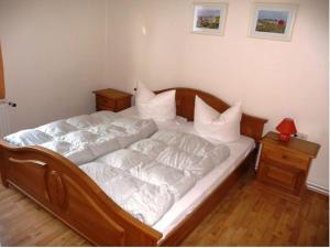 Schlafzimmer mit einem Bett mit weißer Bettwäsche und Kissen in der Unterkunft Ferienwohnung Lara in Zinnowitz