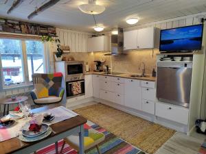 a kitchen with white cabinets and a tv on the wall at Mummon Mökki in Lokka