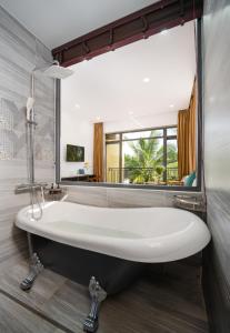 a bath tub in a bathroom with a large mirror at Flower Villa in Hoi An