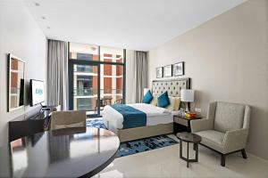 Habitación de hotel con cama, escritorio y mesa. en Aliving Elite Studio Celestia A Dubai South en Dubái