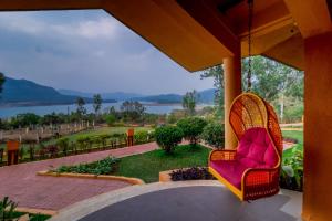 a chair on a porch with a view of the water at Residency Lake Resort & Spa in Mulshi