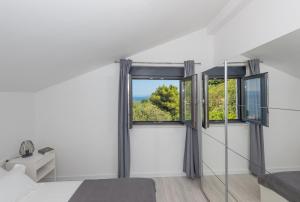 a bedroom with a bed and two windows at Sun Paradise Apartment in Podgora