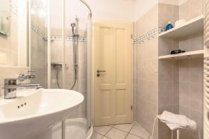 uma casa de banho branca com um lavatório e um chuveiro em Villa Strandperle, App 05 - nur 20m zum Strand, TOPLAGE em Binz