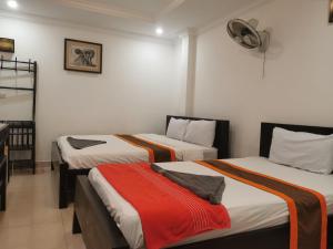 a room with two beds and a fan on the wall at CENTRAL BACKPACKER in Siem Reap