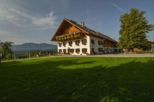 ein großes Haus mit einem großen grünen Feld davor in der Unterkunft Biohof-Rechenmacher in Uffing