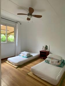 two beds in a room with a ceiling fan at Séjour zen dans l'intense sud sauvage de l'île in Saint-Joseph