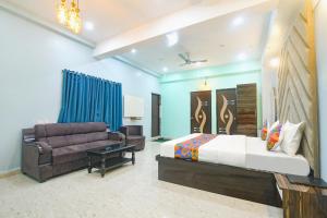 a bedroom with a king sized bed and a couch at FabExpress MU Club in Patna