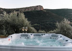 a hot tub with two wine glasses in it at Elaia Rest House in Fréngaina