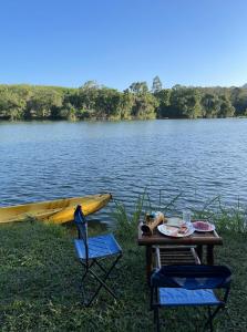 une table, deux chaises et un bateau sur un lac dans l'établissement Sawasdee Lagoon Camping Resort, à Ban Lam Pi