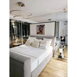 - une chambre avec un grand lit blanc et un lustre dans l'établissement Appartement vue océan location voiture santa monica, à Praia